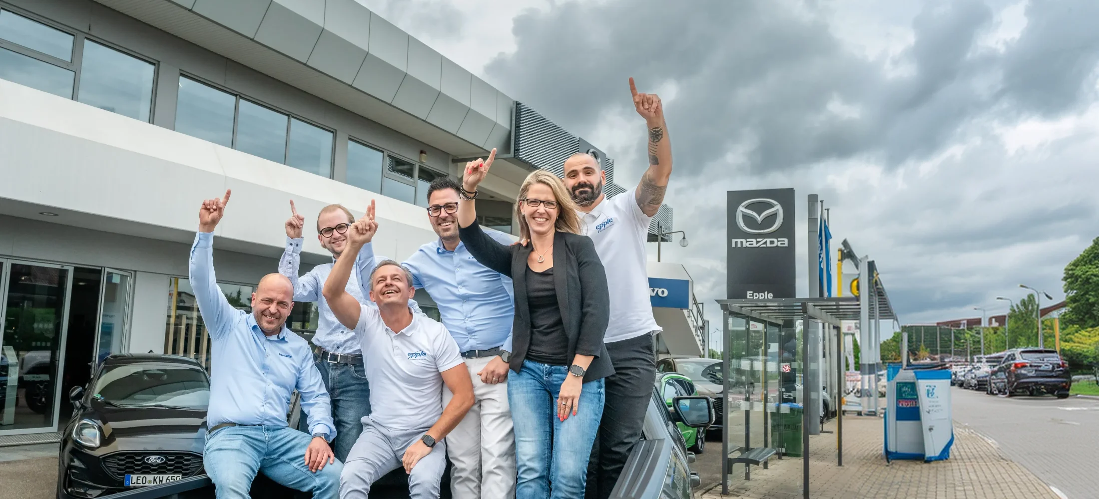 Mitarbeiter stehen auf der Ladefläche eines Fords und zeigen mit dem Finger nach oben