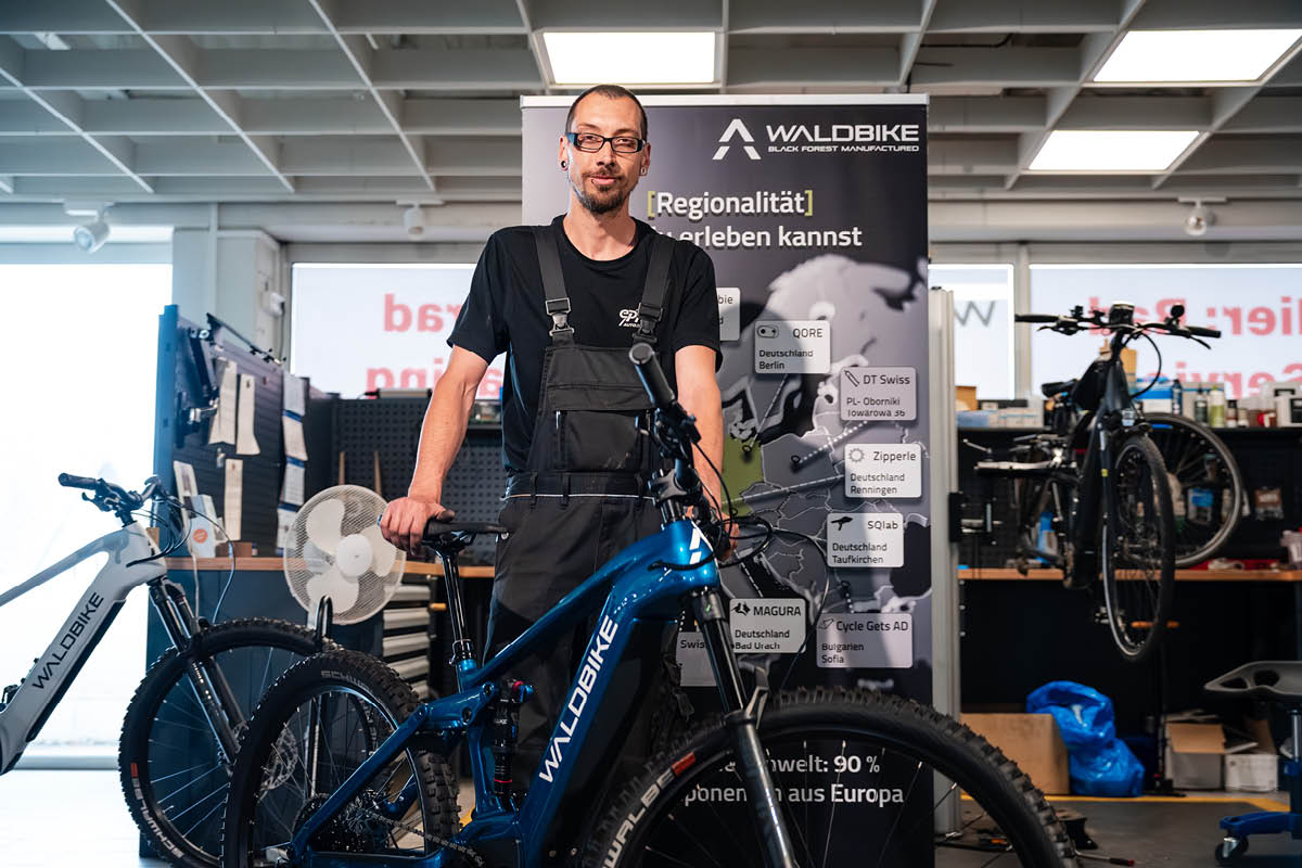 Mitarbeiter steht mit Rad in der Werkstatt